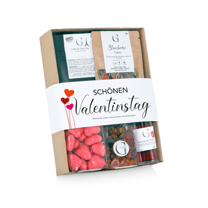 Genial Genießen Valentinstag Geschenkset mit ausgewählten Feinkostspezialitäten wie Dip-Gewürzen, Balsam, Tee und süßen Herz-Snacks in dekorativer Geschenkverpackung für romantische Genussmomente.